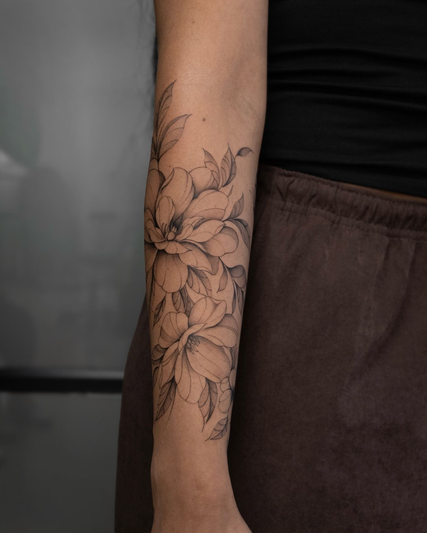 Tatuaje de flores de magnolia en fine line con sombreado suave, antebrazo